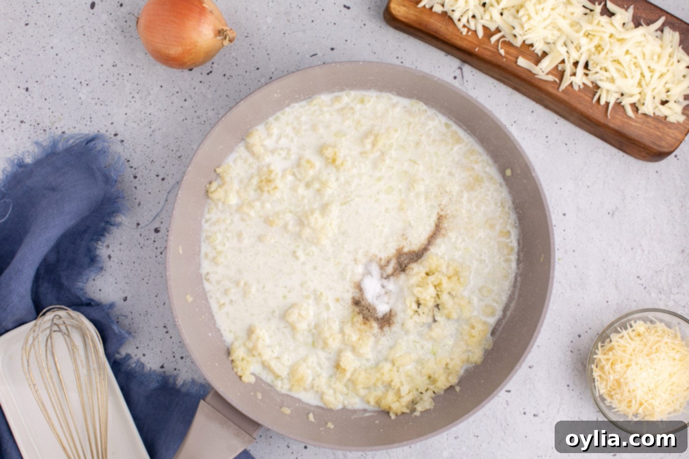 adding milk, salt, and pepper to skillet of onion and garlic