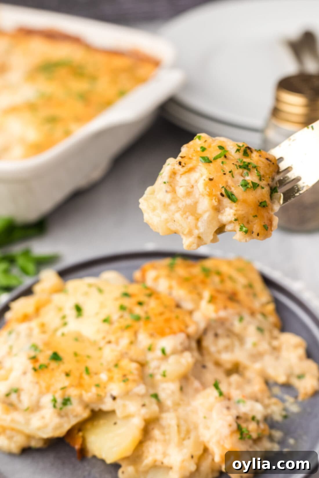Scalloped Potatoes on a fork held above a plate of Scalloped Potatoes