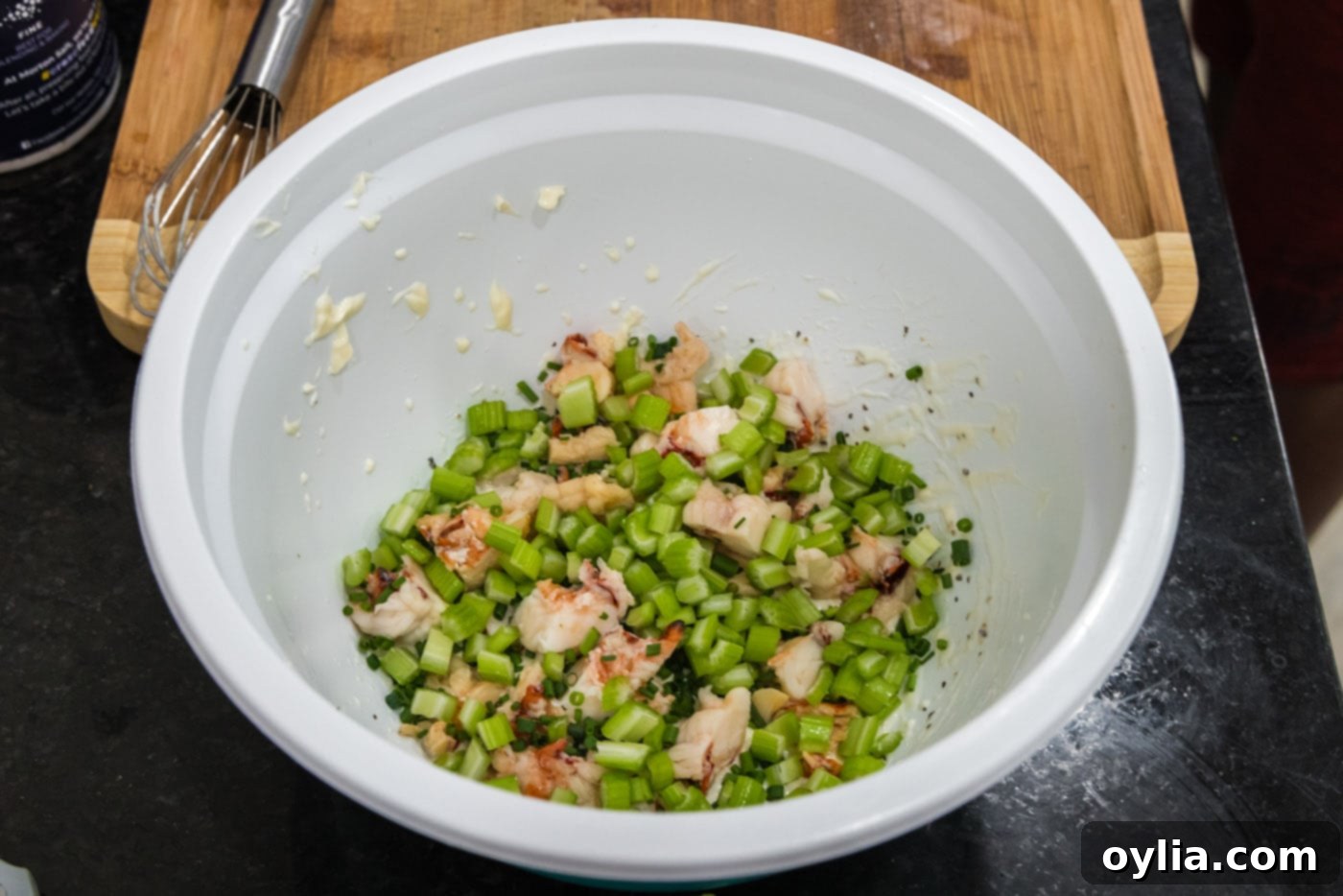 chives and celery added to bowl of dressing and lobster meat
