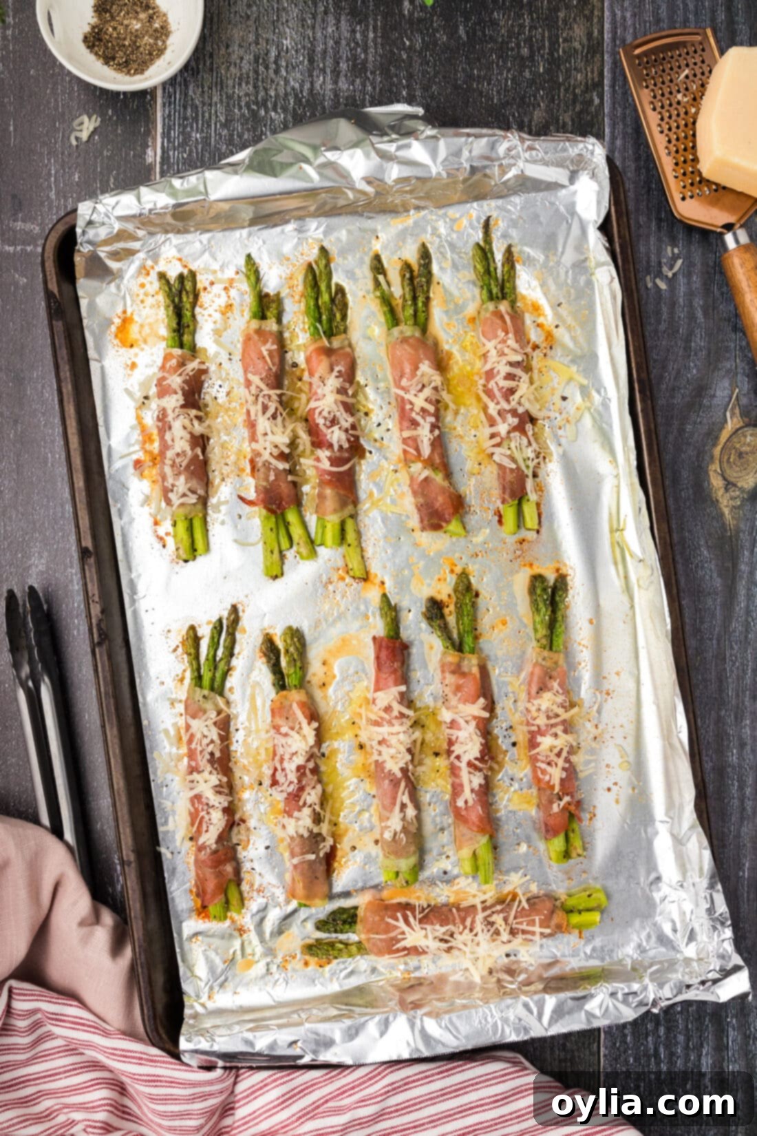 Prosciutto Wrapped Asparagus arranged on a sheet pan before baking