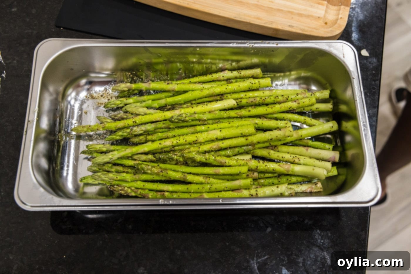 Seasoned asparagus spears resting in a tray, ready for wrapping