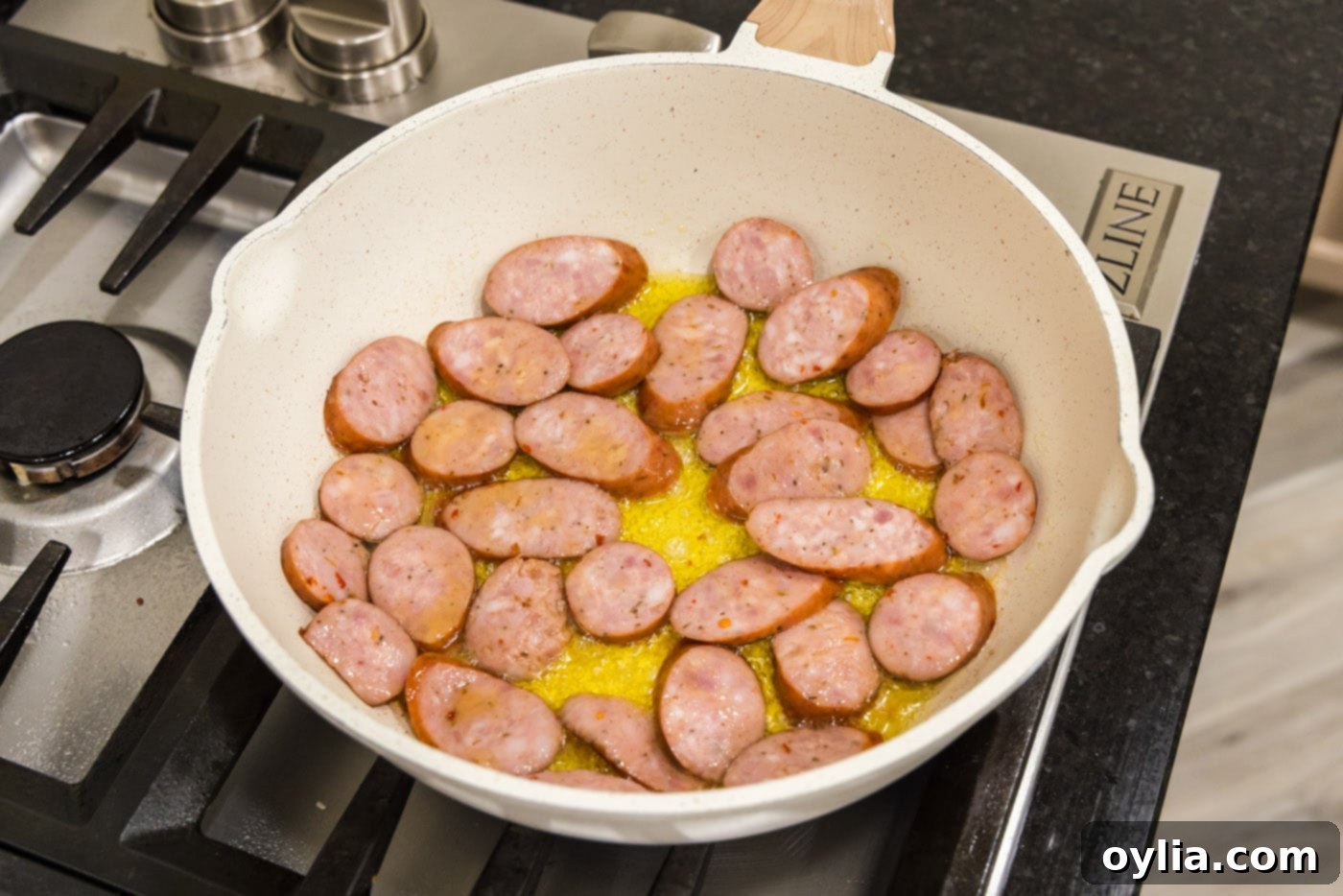 sliced andouille sausage in a skillet with oil