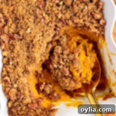 Spoonful of Sweet Potato Souffle resting in a baking dish of Sweet Potato Souffle, highlighting its delicious texture.