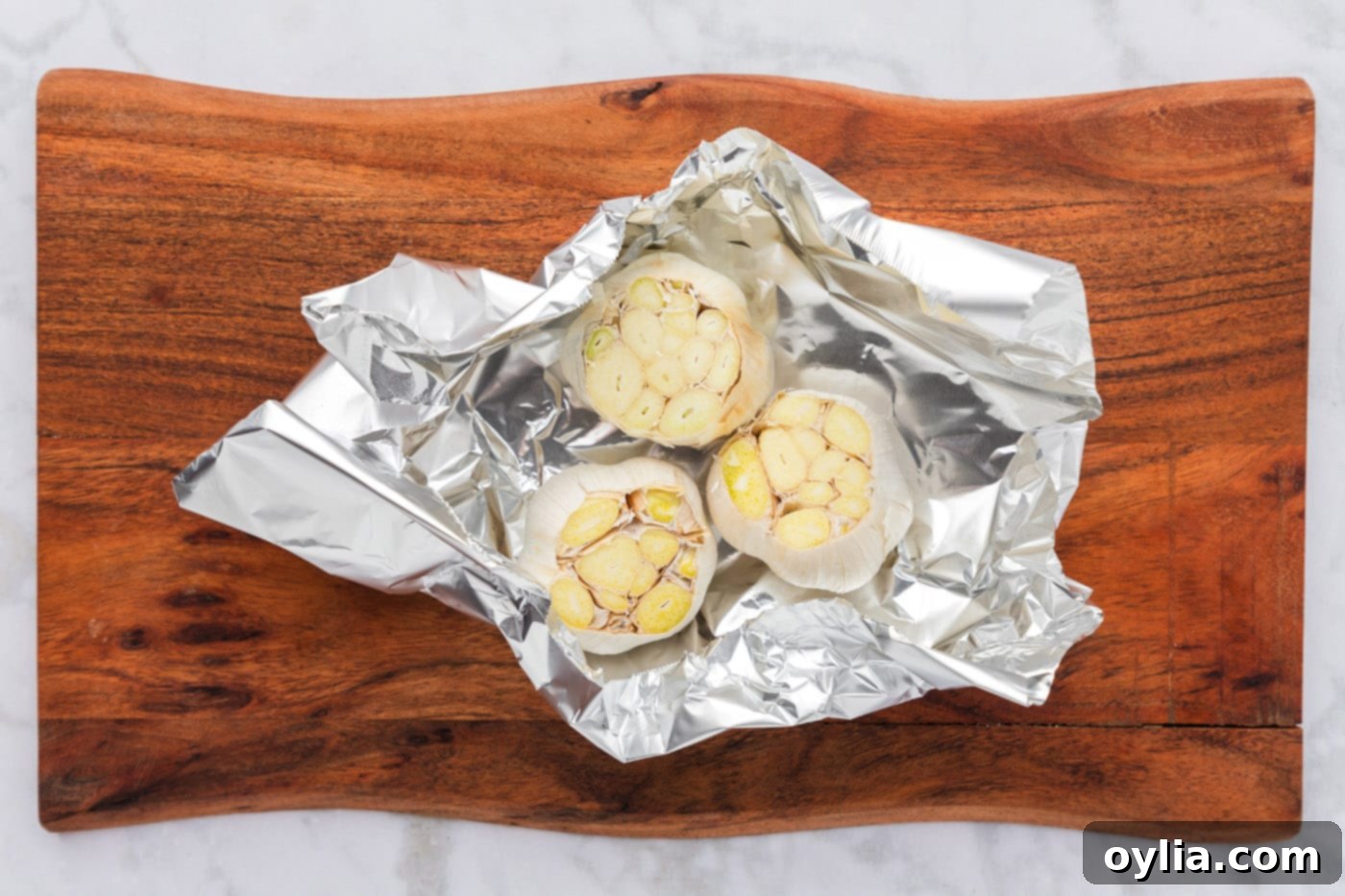 sliced whole bulbs of garlic in aluminum foil