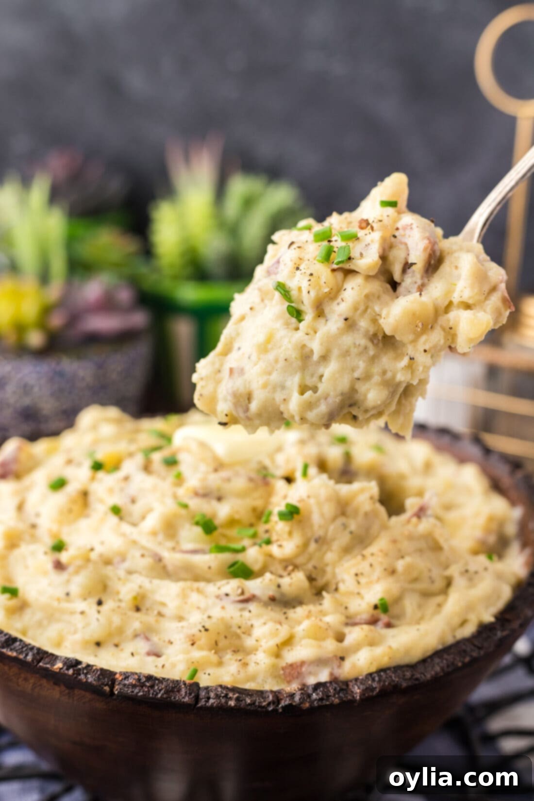 Spoonful of creamy Garlic Mashed Potatoes being lifted above a bowl, showing the fluffy texture.