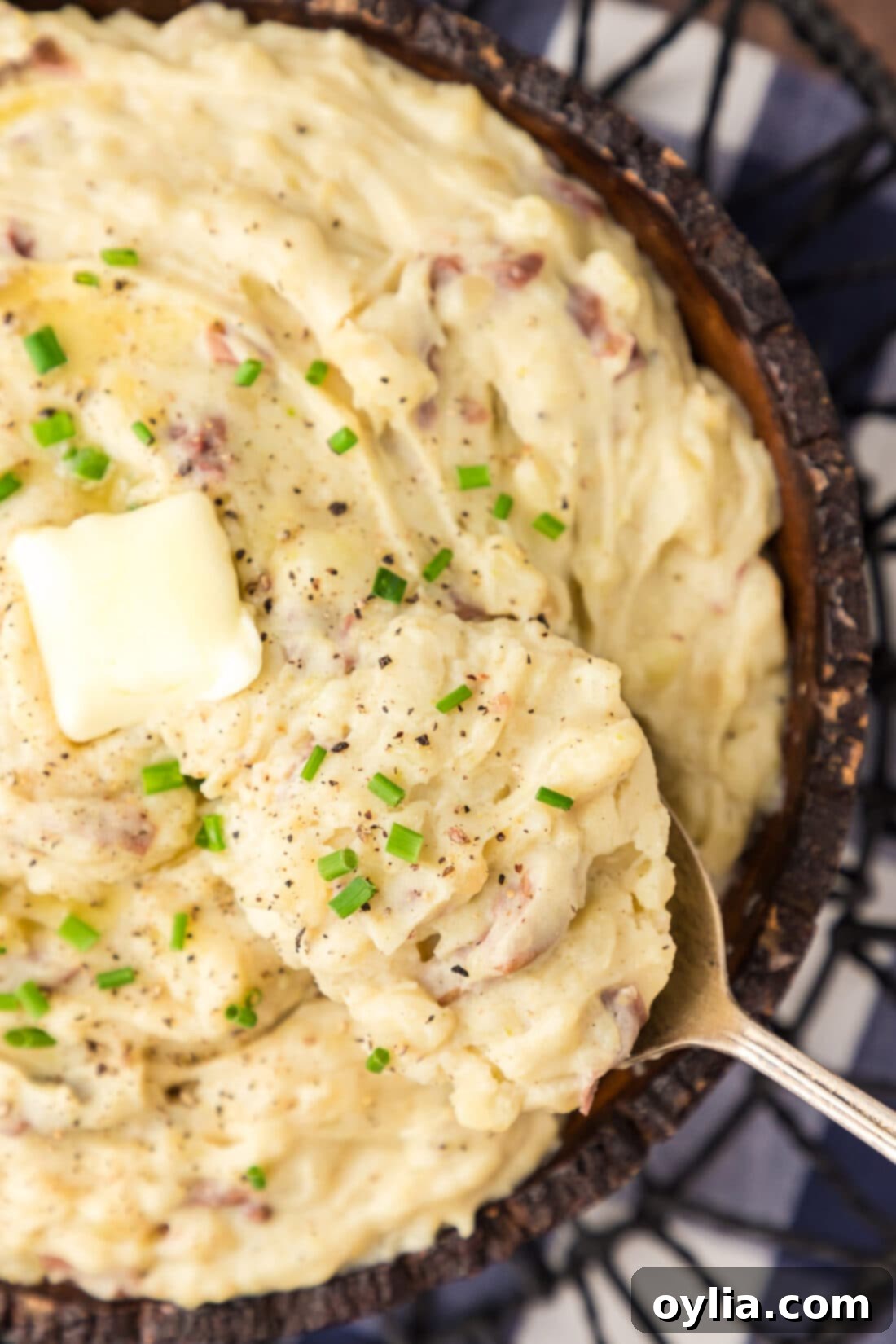 Close up photo of a spoon scooping creamy Garlic Mashed Potatoes from a bowl.
