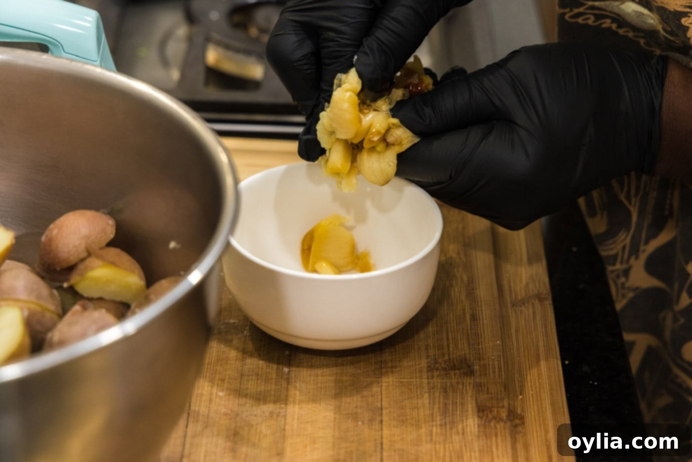 adding roasted garlic to a bowl of hot potatoes