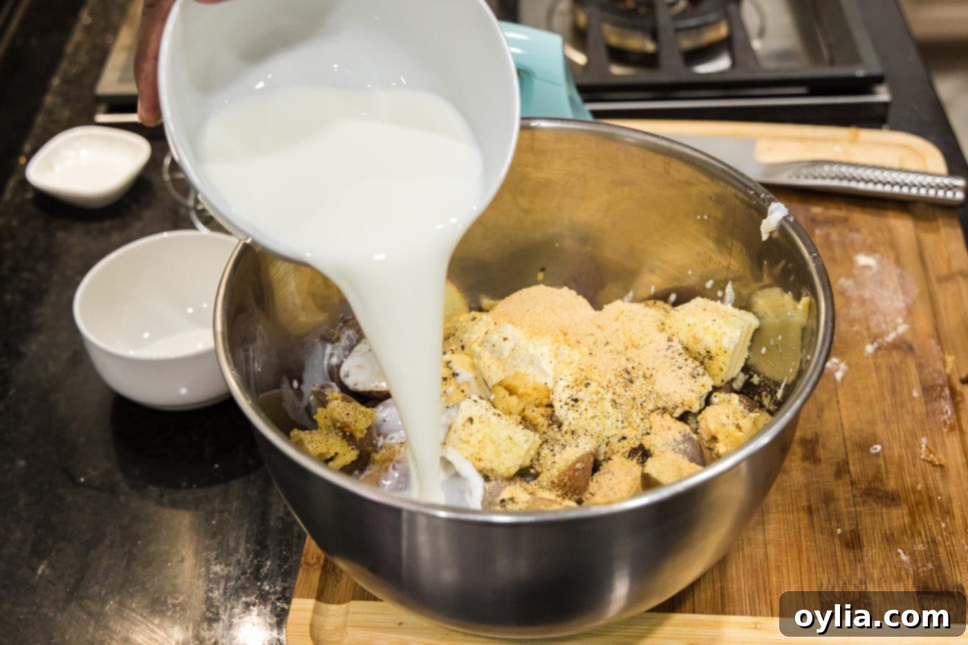pouring heavy whipping cream into bowl of sour cream, butter, potatoes, and garlic