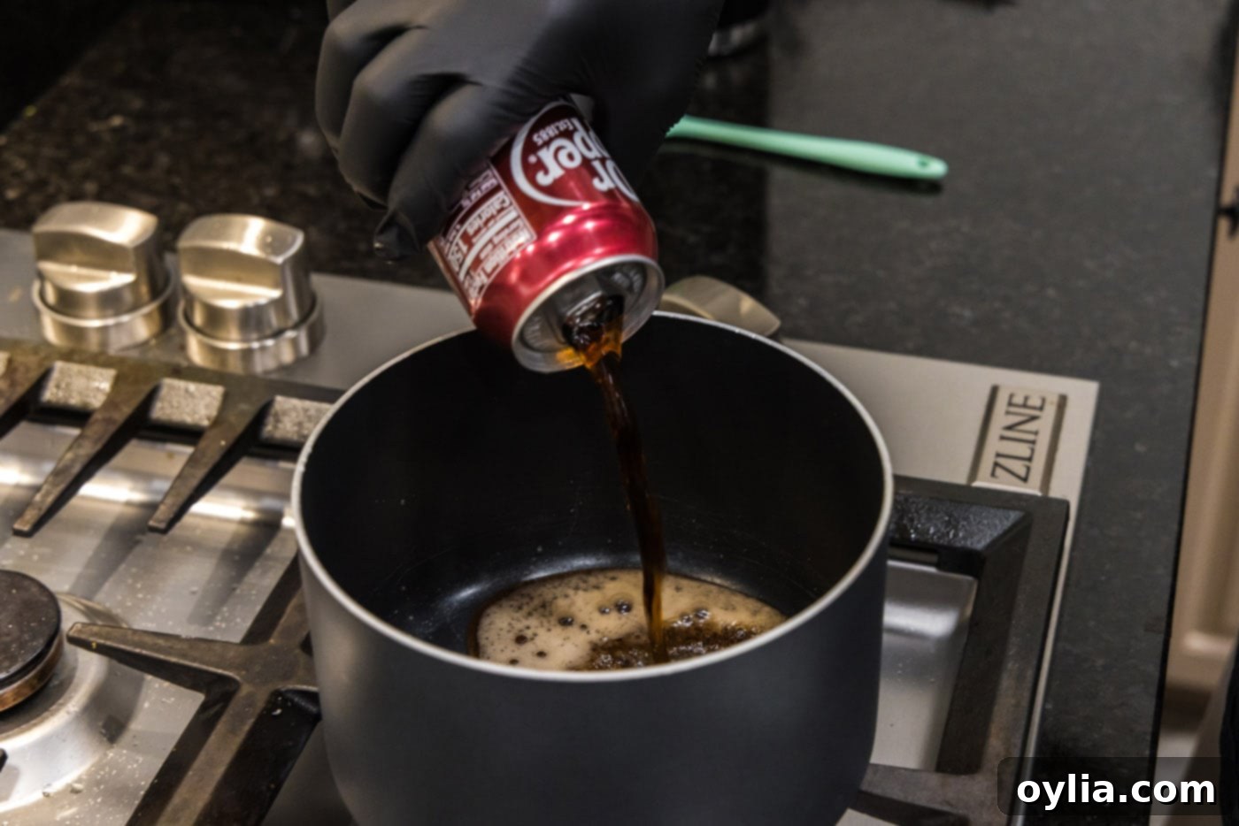 pouring dr. pepper into a saucepan with other ingredients