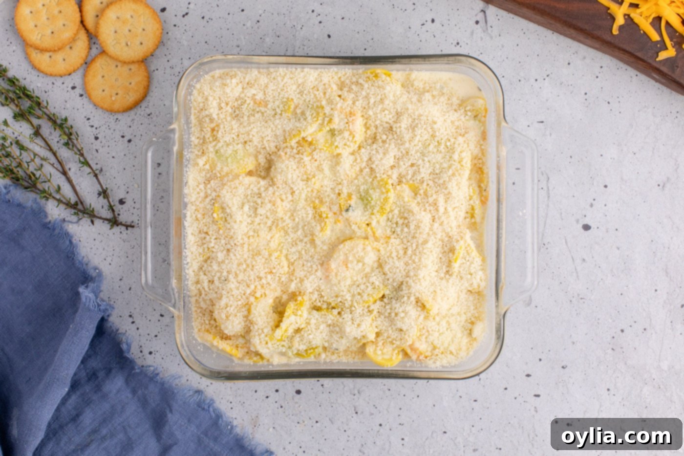 parmesan cheese being sprinkled on top of the squash casserole filling