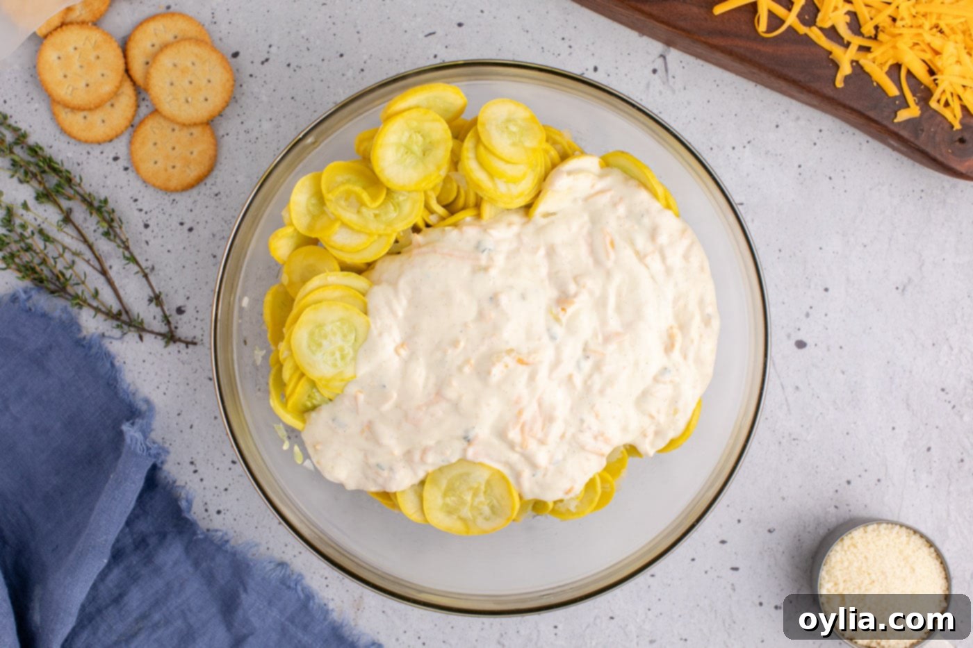 adding sour cream filling to sliced yellow squash in a mixing bowl, showing the mixing process