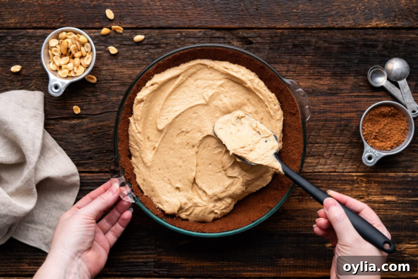 Spreading the creamy peanut butter pie filling smoothly over the chocolate graham cracker crust in the pie plate.