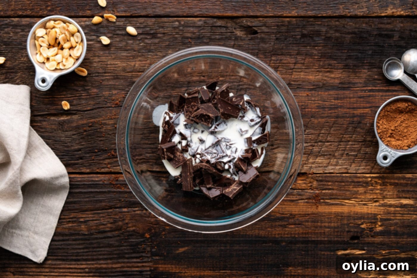 Chopped dark chocolate in a bowl with hot heavy whipping cream poured over it, beginning the process of making ganache.