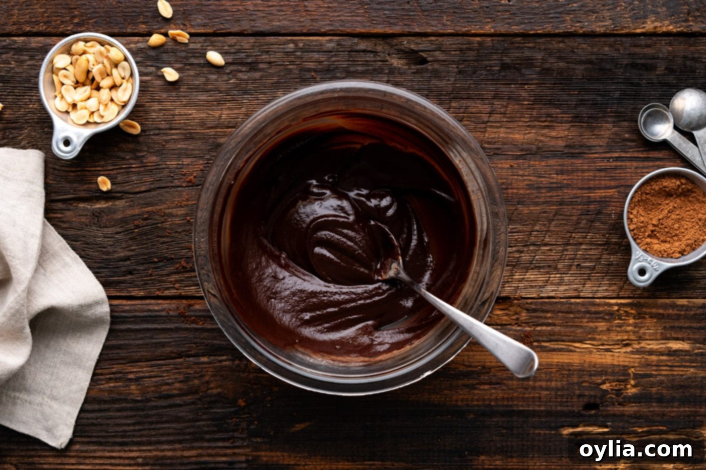 Smooth, glossy chocolate ganache in a mixing bowl with a spoon, perfectly prepared and ready for use.
