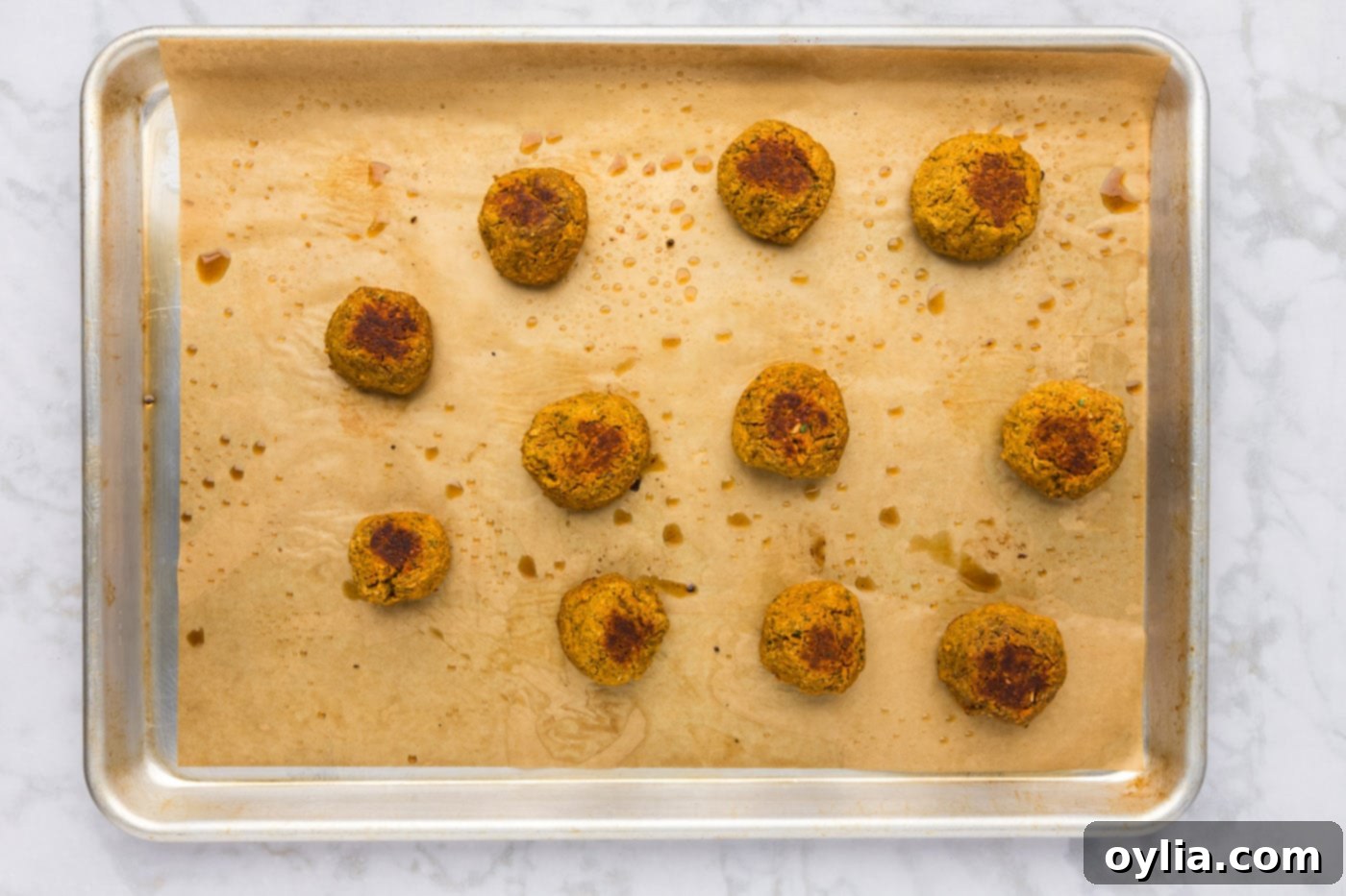 Baked lentil meatballs are visible on a cookie sheet, golden brown and perfectly cooked.