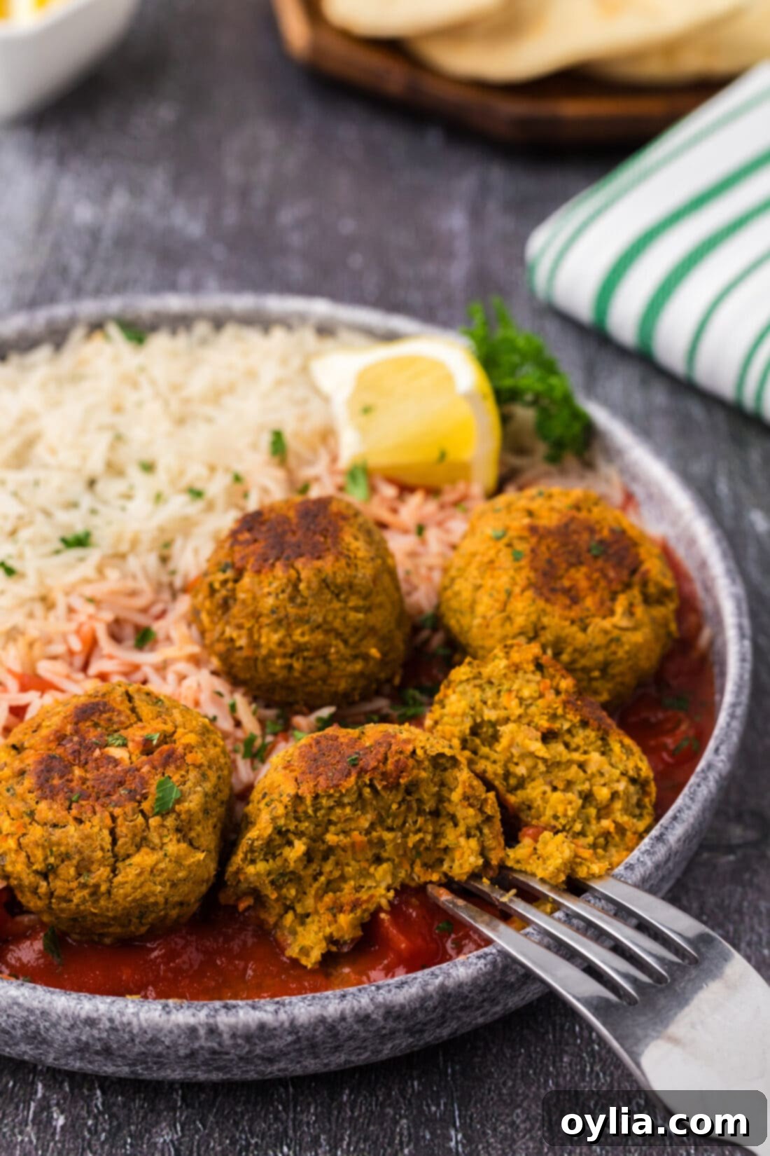 Close up photo of a Lentil Meatball split in half with a fork, showing its tender, textured interior.