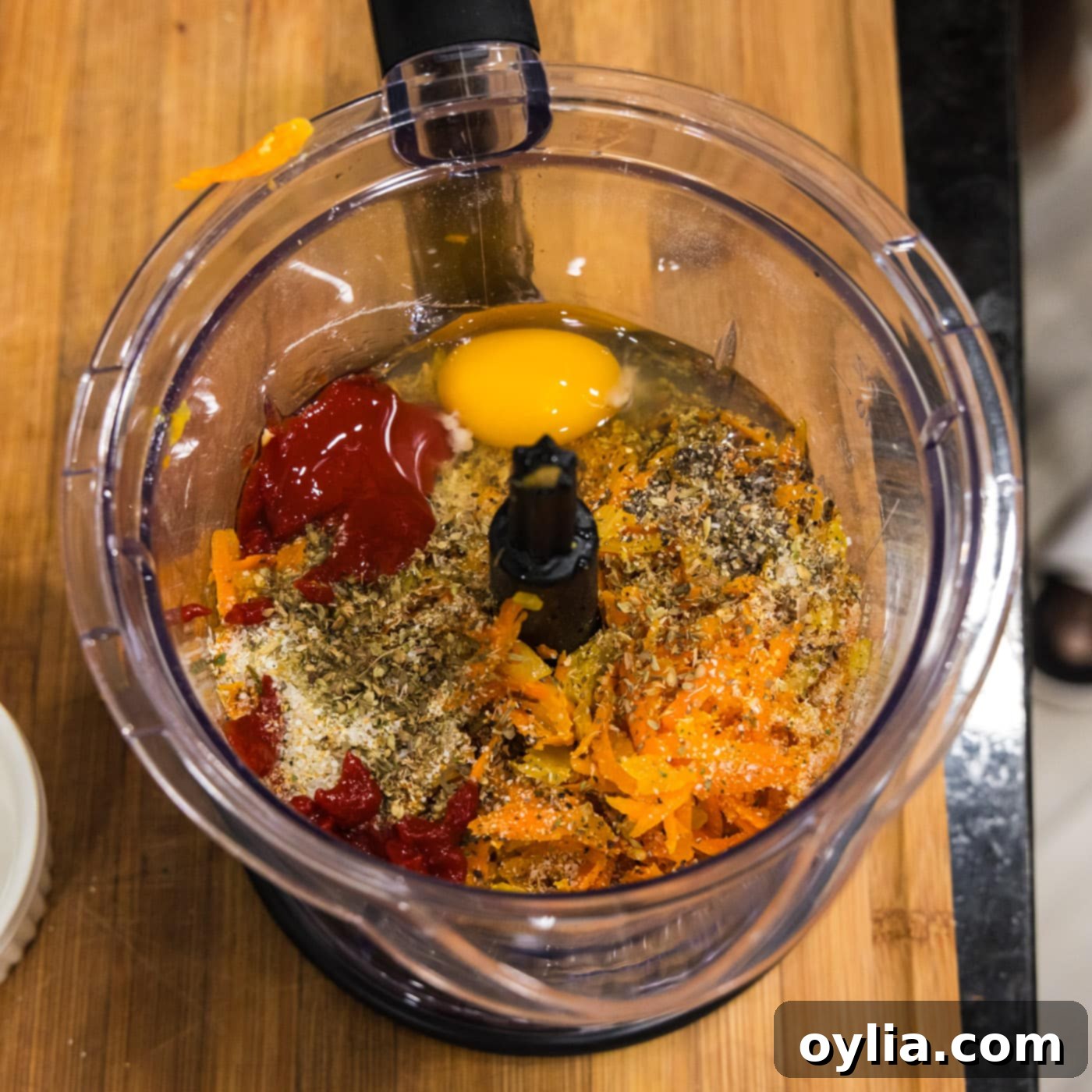 All lentil meatball ingredients, including cooked lentils, sautéed vegetables, spices, tomato paste, and egg, are added to a food processor.