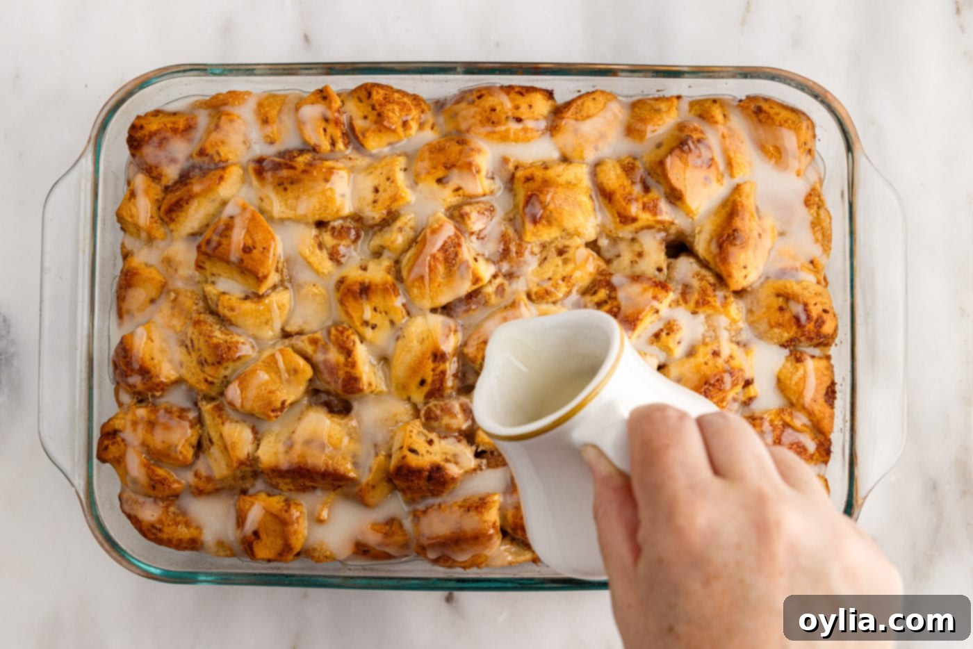 pouring icing over cinnamon roll casserole