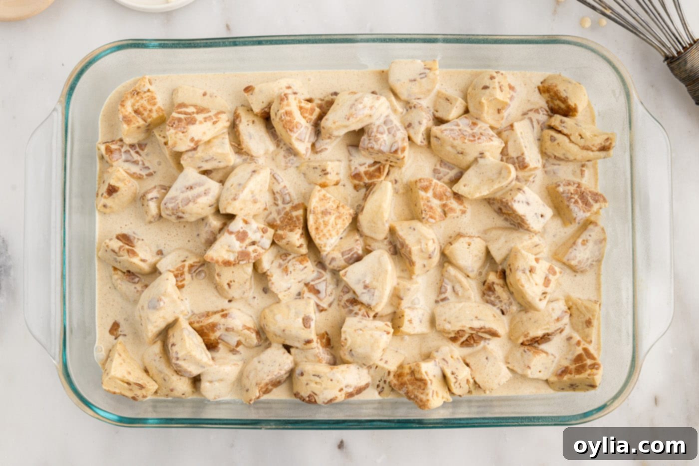cream mixture poured over chopped cinnamon rolls in a baking dish