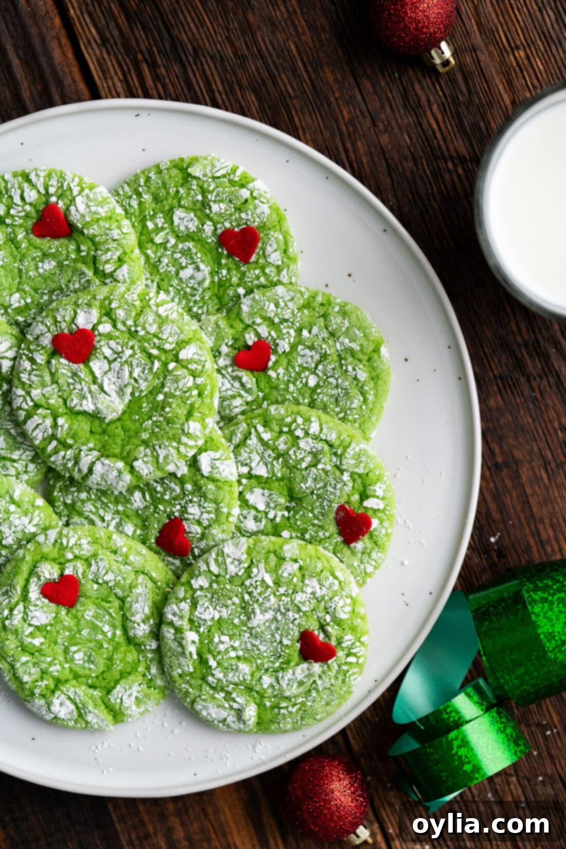 Grinchy Holiday Cookies 3 Overhead photo of a half plate of bright green Grinch Cookies, dusted with powdered sugar and topped with a red candy heart, ready to be served.