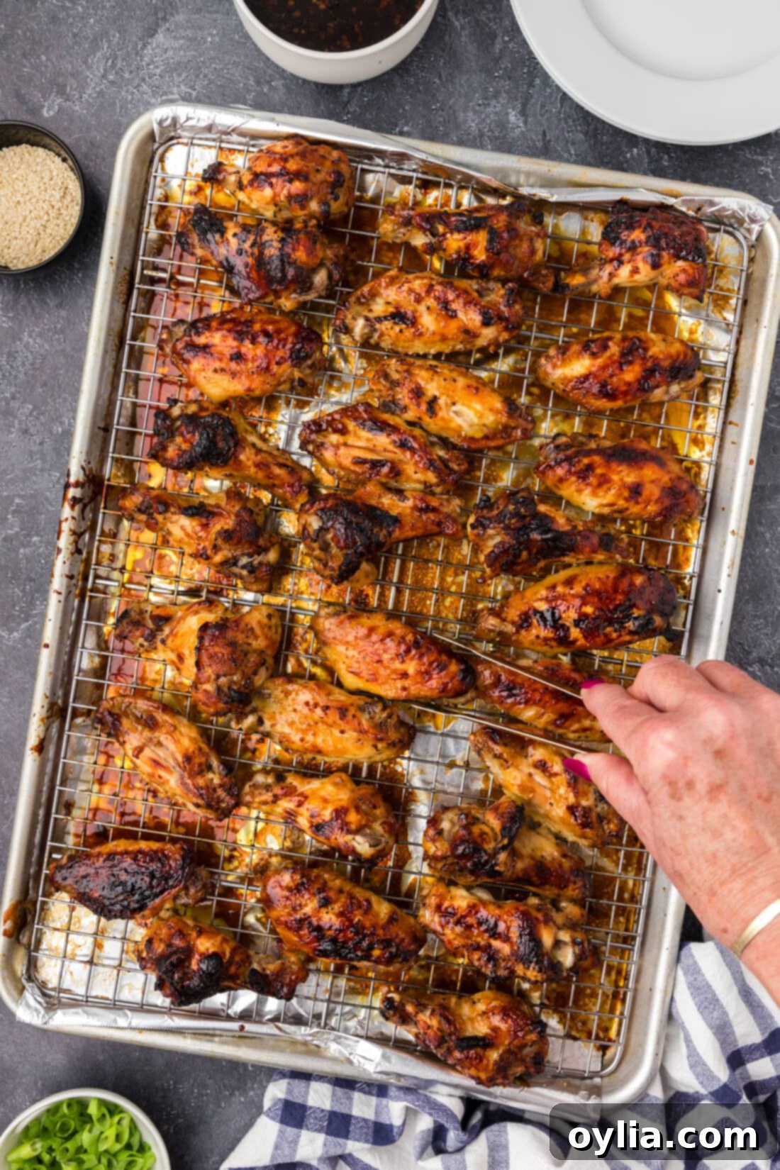 Sticky Honey Garlic Wings 2 Hand grabbing a Honey Garlic Chicken Wing off a sheet pan of Honey Garlic Chicken Wings