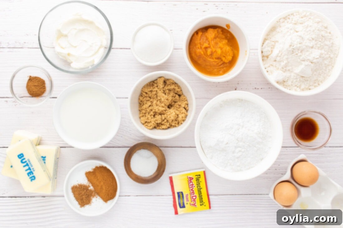 Assorted ingredients for pumpkin cinnamon rolls, including flour, butter, pumpkin puree, spices, and yeast, laid out on a wooden surface.