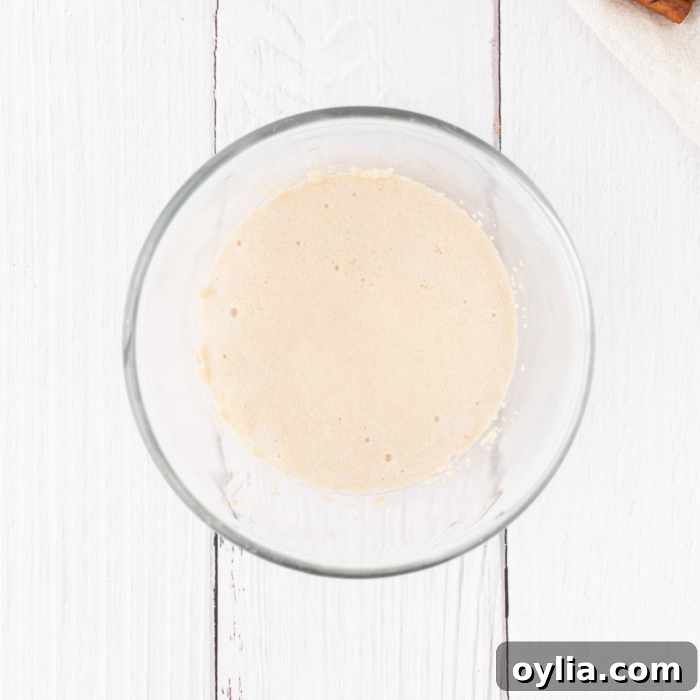 Active dry yeast in a small bowl with sugar and warm water, showing a foamy layer on top after activation.