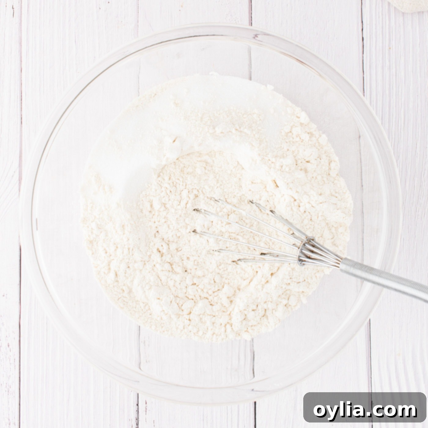A bowl containing flour, sugar, and salt being whisked together, preparing for the pumpkin cinnamon roll dough.