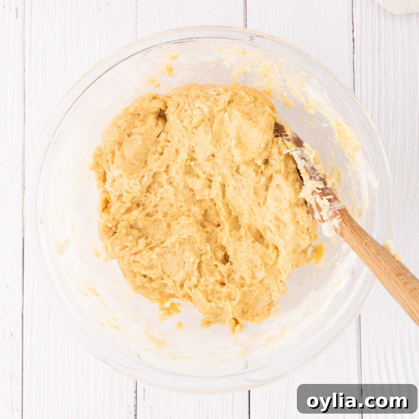 Pumpkin cinnamon roll dough after mixing, shown in a large mixing bowl.