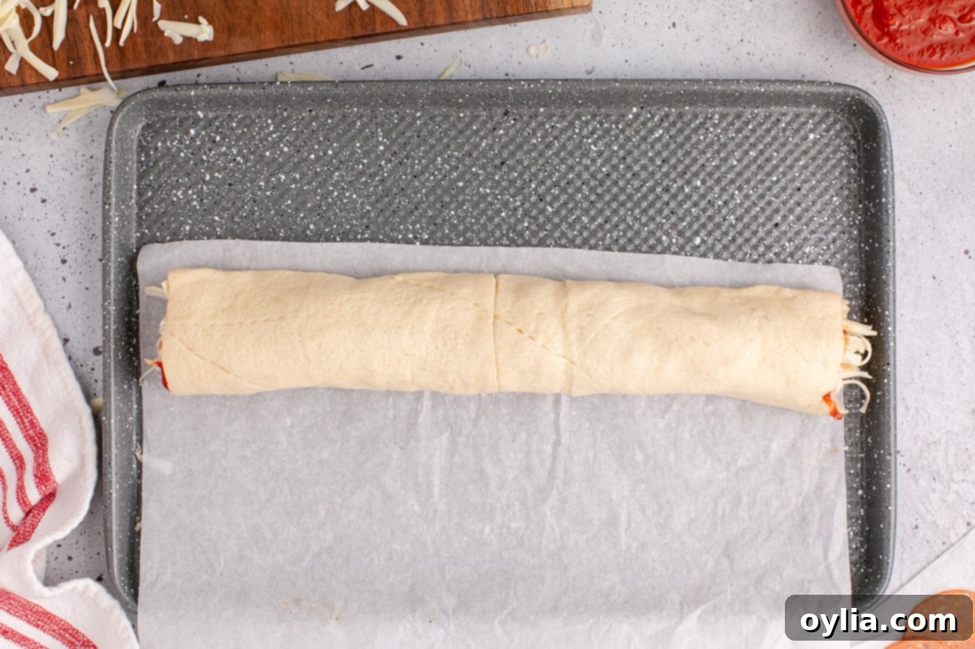 The completely rolled crescent dough log, ready to be sliced into individual pizza pinwheels.