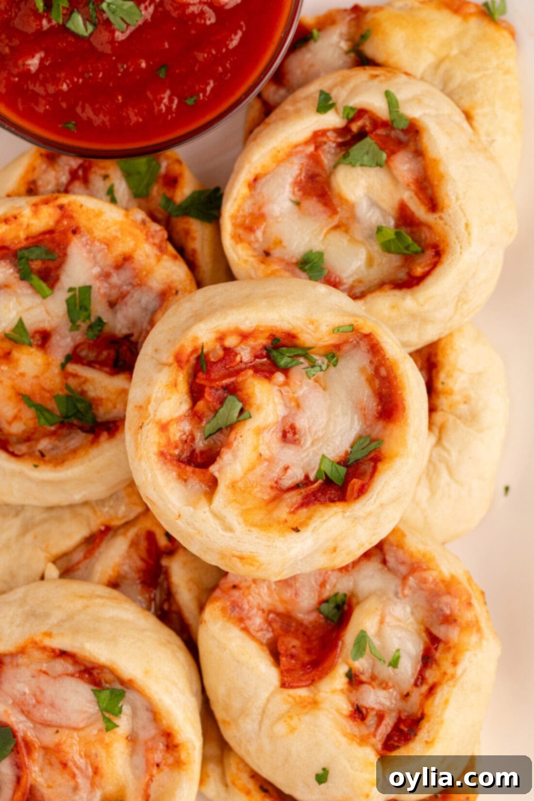 Cheesy Pizza Pinwheels 13 A close-up view of three freshly baked pizza pinwheels, showcasing the swirled layers of dough, melted cheese, and pepperoni.