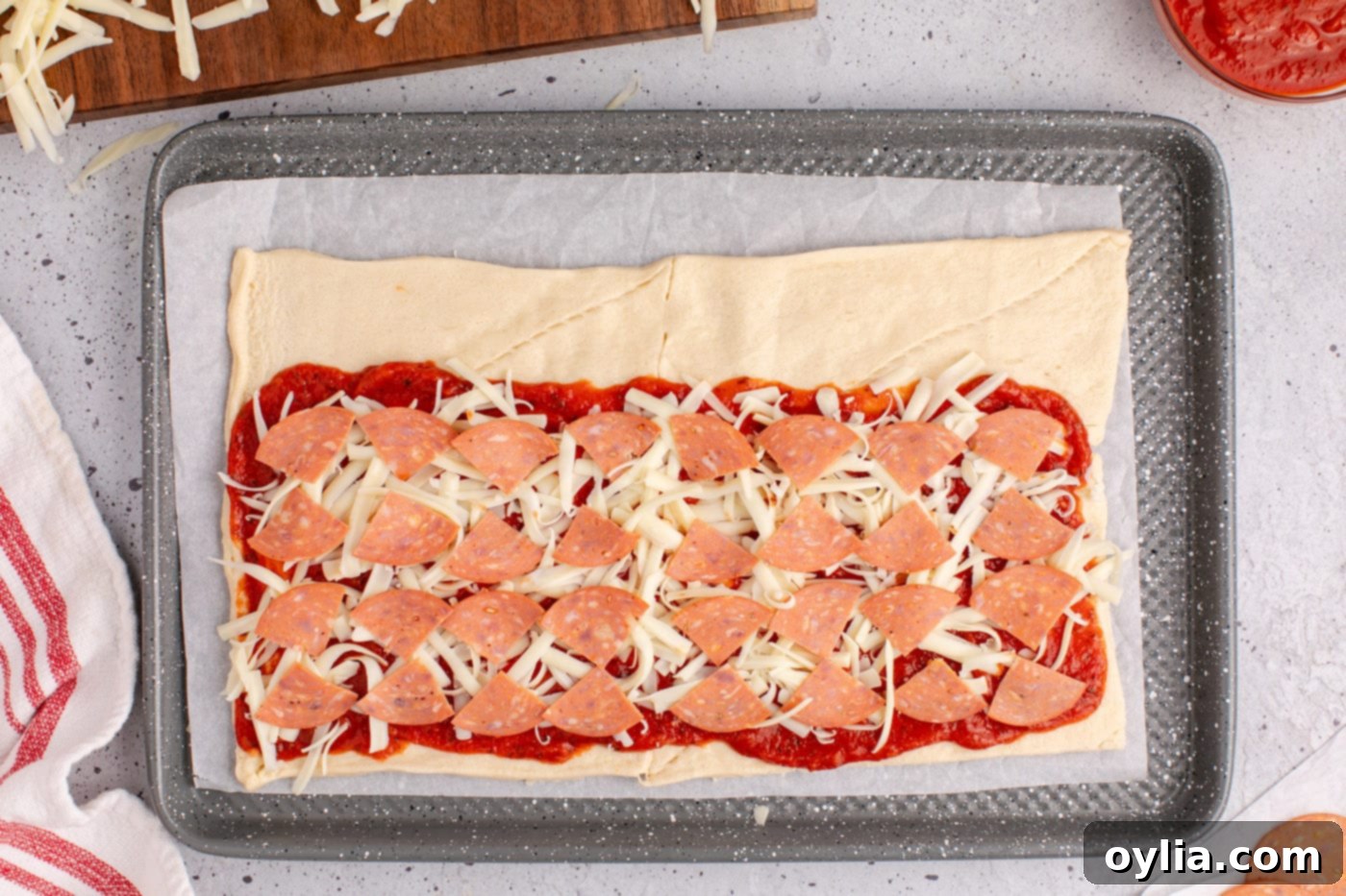 Chopped pepperoni slices evenly distributed over the cheese and pizza sauce on crescent dough.