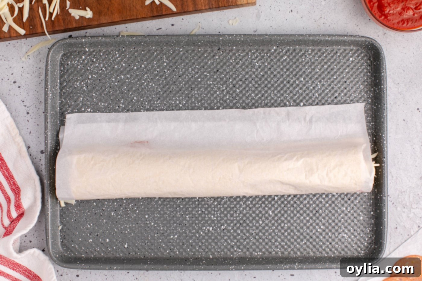 Crescent roll dough with toppings being rolled up tightly into a log shape.