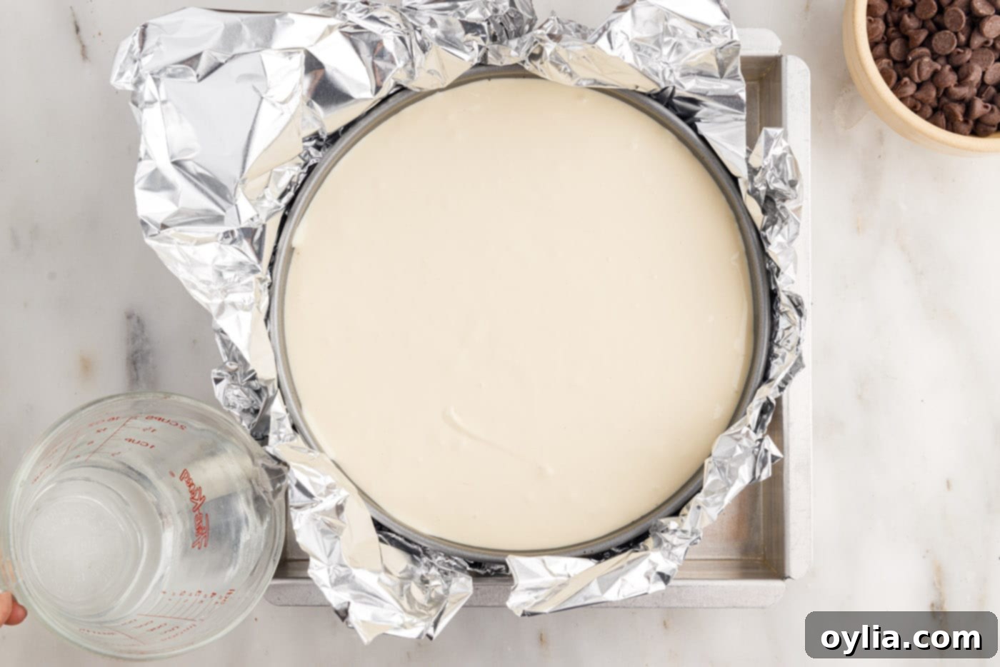 The springform pan with cheesecake batter, securely wrapped in two layers of aluminum foil, ready for the water bath.
