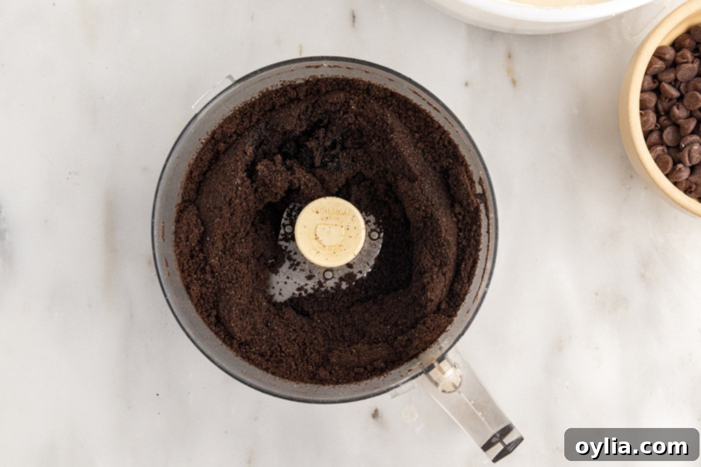 Finely blended Oreo cookie crumbs in a food processor, ready for mixing with butter.