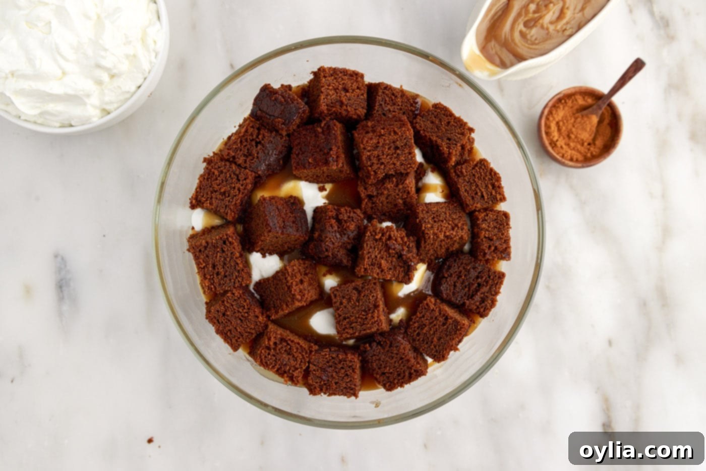 Second layer of cubed gingerbread cake placed over the caramel and whipped cream in the trifle bowl.