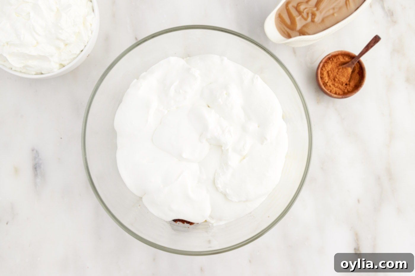 A light and fluffy layer of whipped cream covering the pudding and gingerbread cake in the trifle.