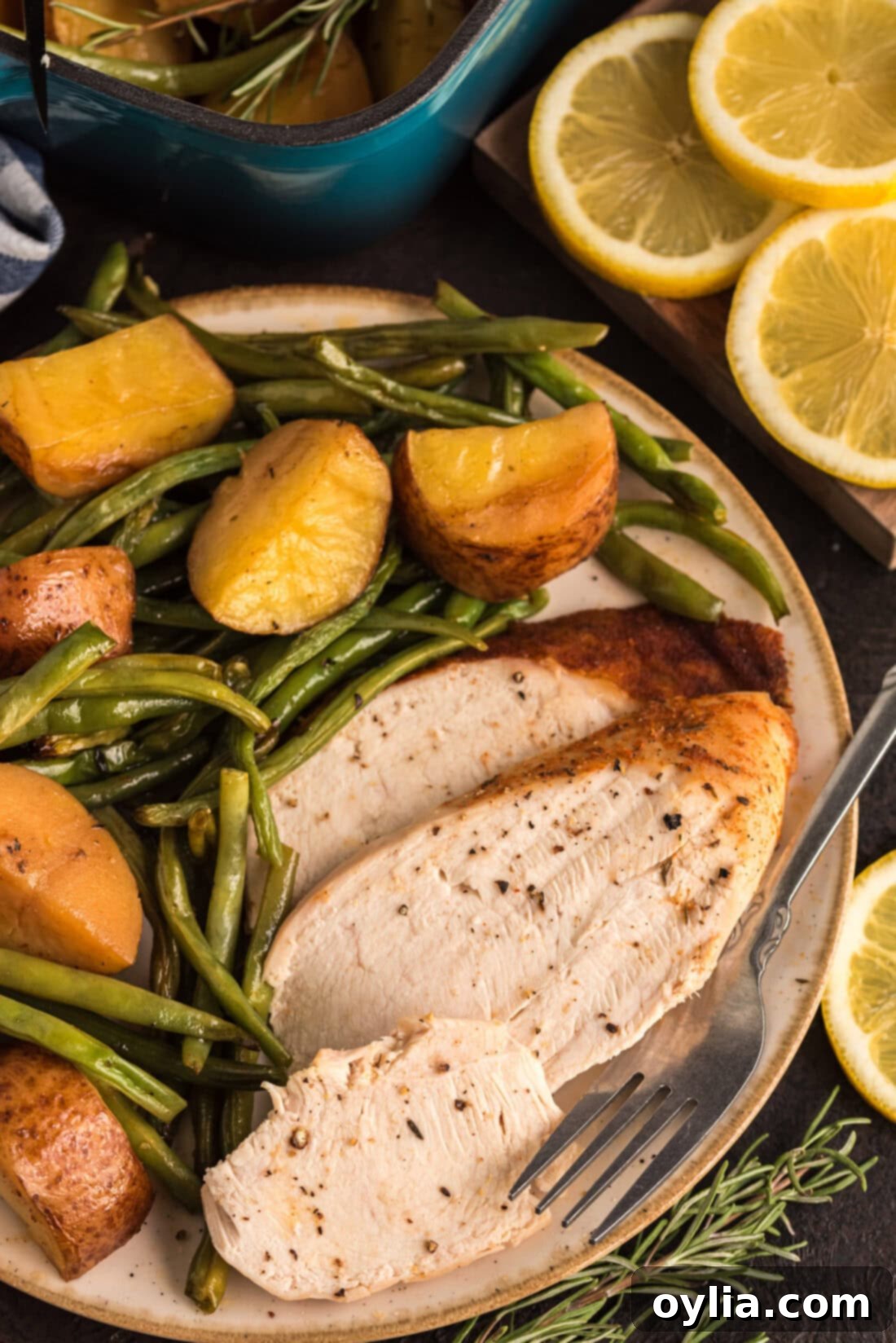 Slices of Slow Roasted Sticky Chicken on a plate with roasted potatoes and green beans