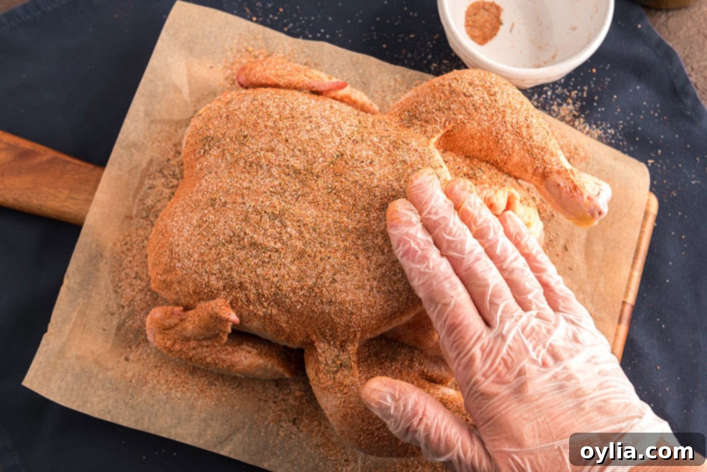 Rubbing whole chicken with seasoning blend, showing hands applying the spice mixture