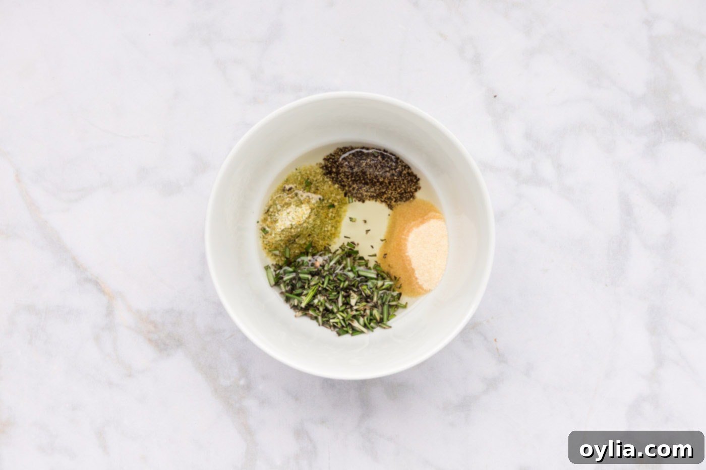 olive oil, pepper, garlic salt, onion powder, and rosemary leaves in a bowl