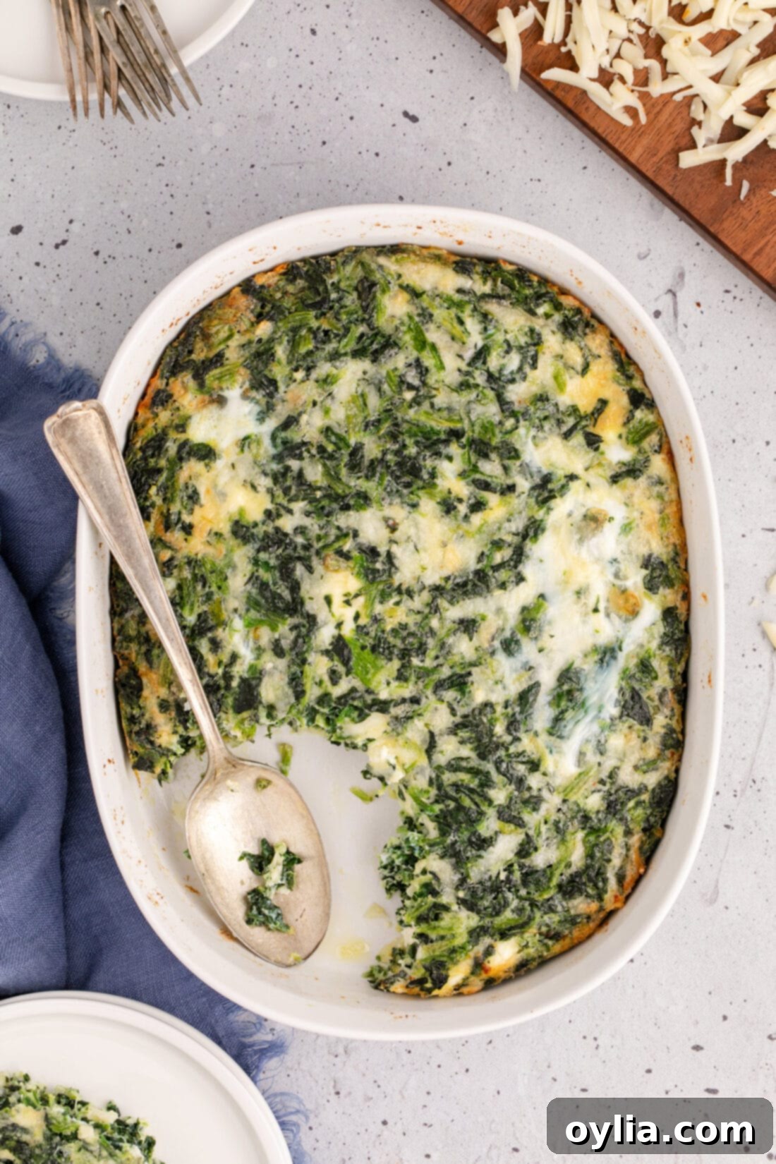 Overhead photo of a spoon resting in a Spinach Souffle, showcasing its fluffy texture and golden crust, perfect as a savory side or brunch item.