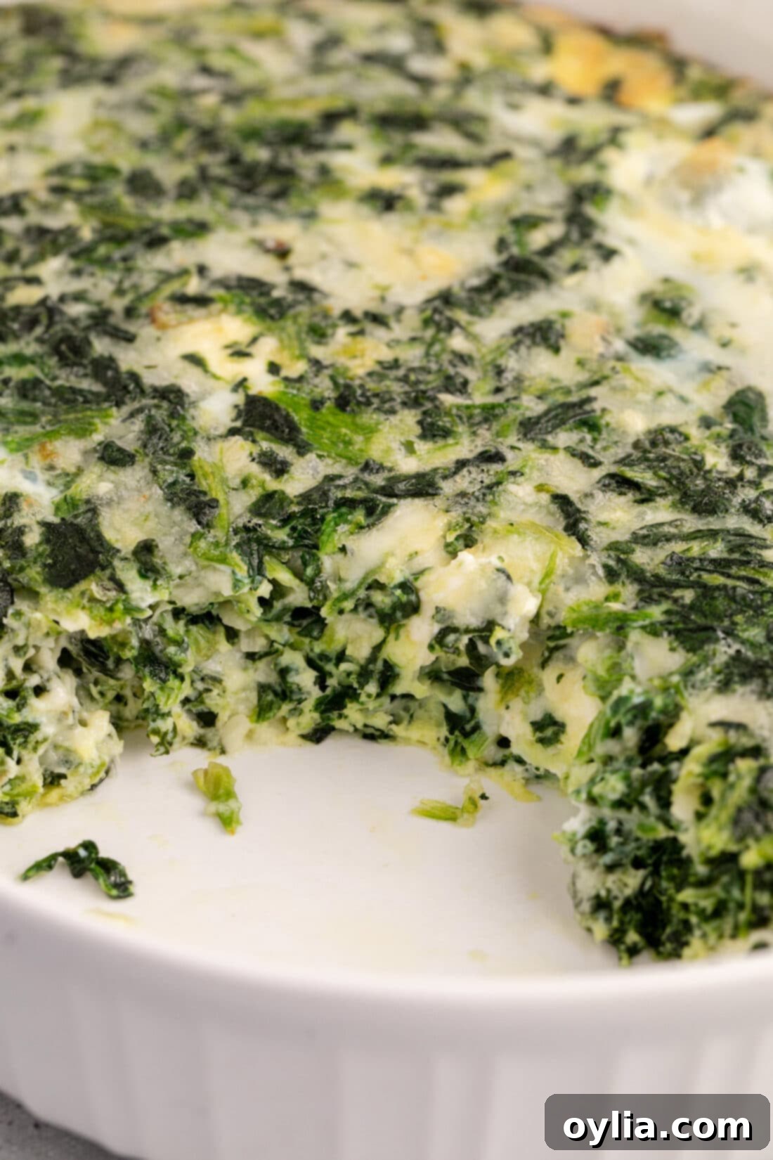 Close up photo of Spinach Souffle with a piece removed, revealing its soft, cheesy interior and the fluffy texture, ready to be served.