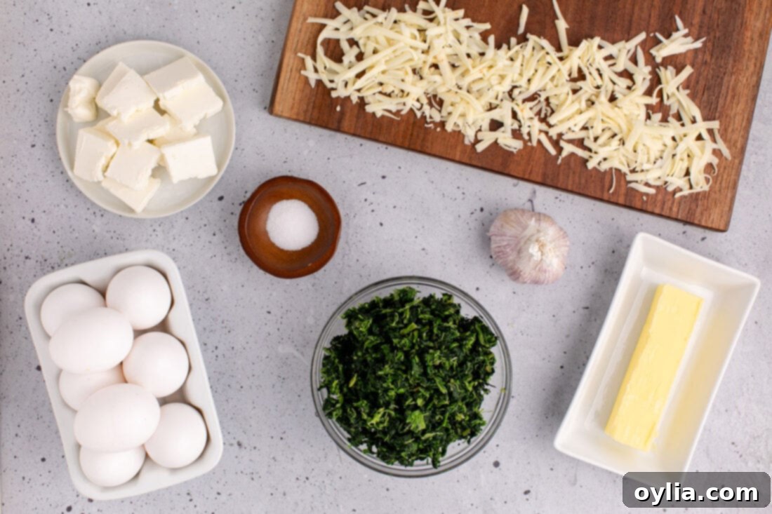 A flat lay of all the essential ingredients for making Spinach Souffle, including eggs, spinach, various cheeses, garlic, and butter, neatly arranged on a counter.