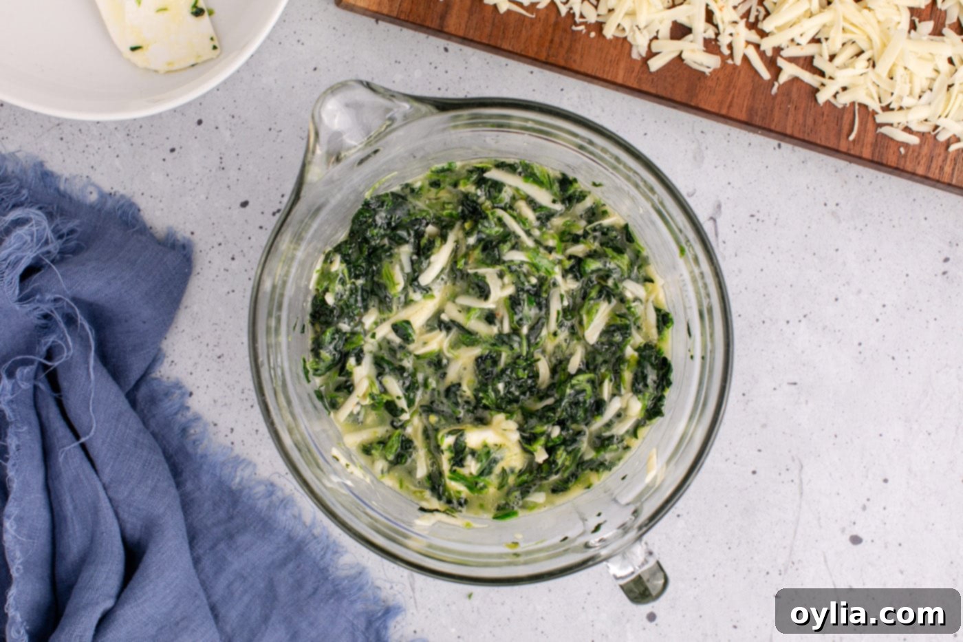 spinach souffle mixture evenly spread in a casserole dish, ready for baking. The surface is smooth and the ingredients are well integrated.