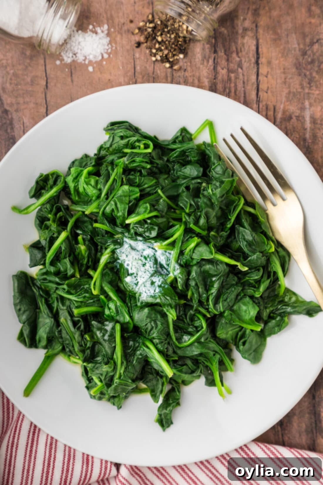 Nutrient-Rich Steamed Spinach 2 Steamed Spinach on a plate with a fork, garnished with a pat of butter and a sprinkle of salt