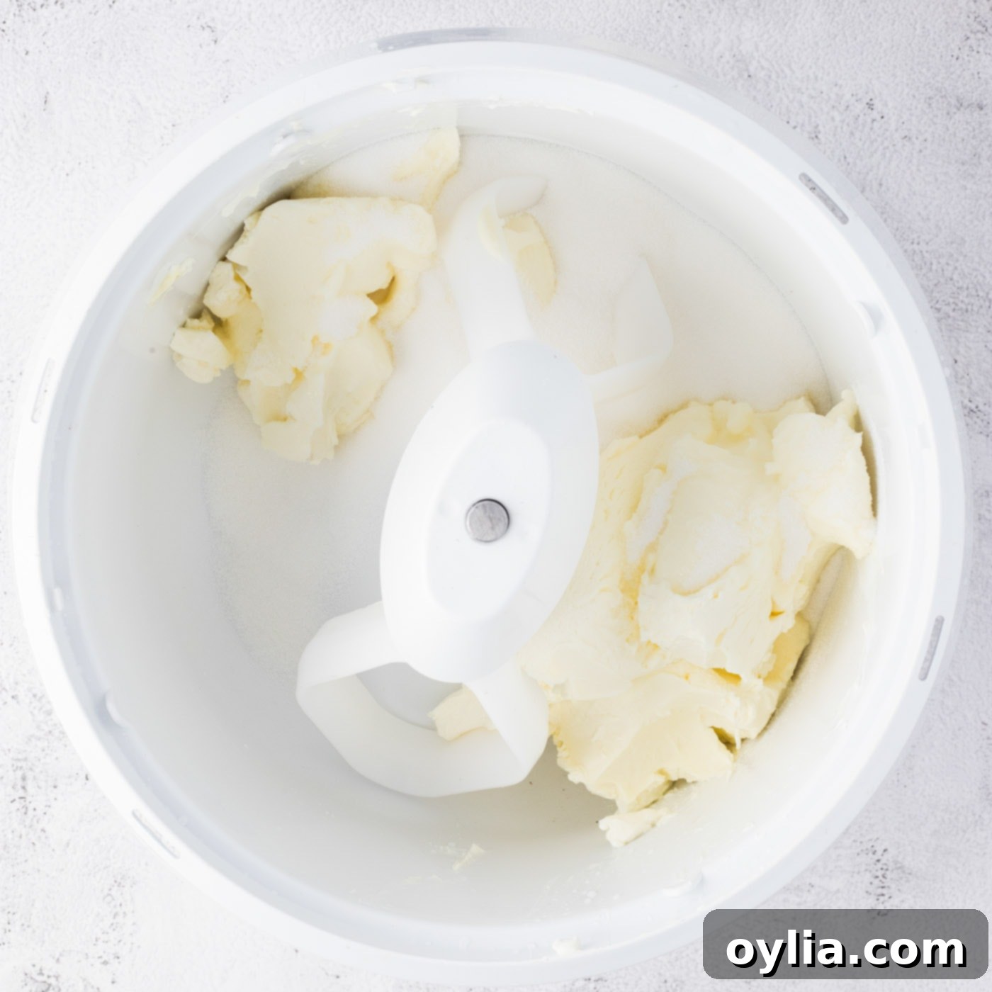Cream cheese and sugar combined and being mixed in a bowl.