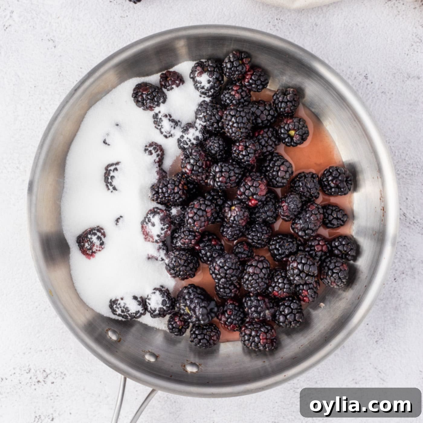 Blackberries, sugar, and fruit nectar simmering in a saucepan for the sauce.