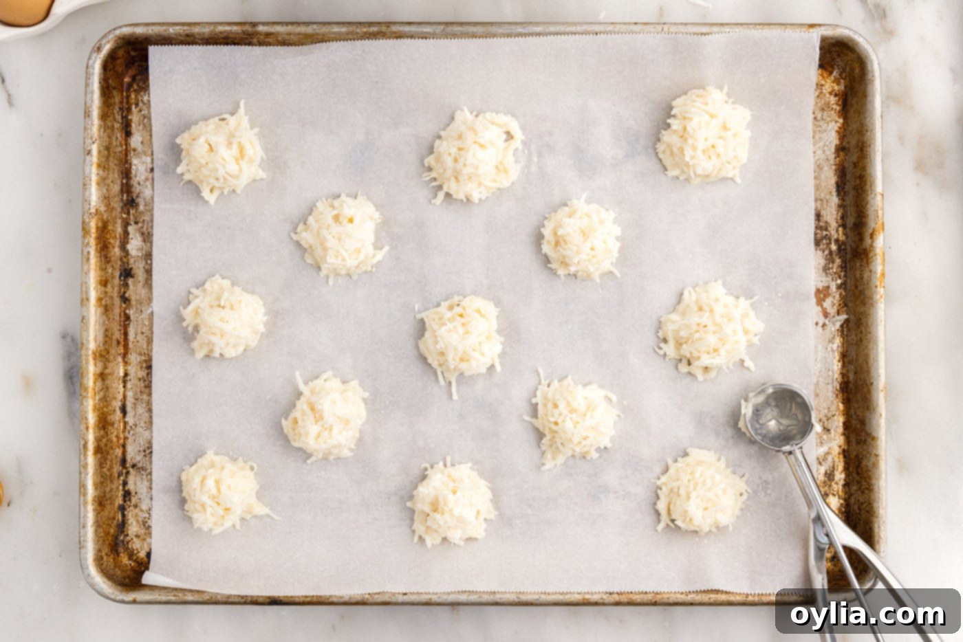 Mounds of coconut macaroons on a baking sheet before baking