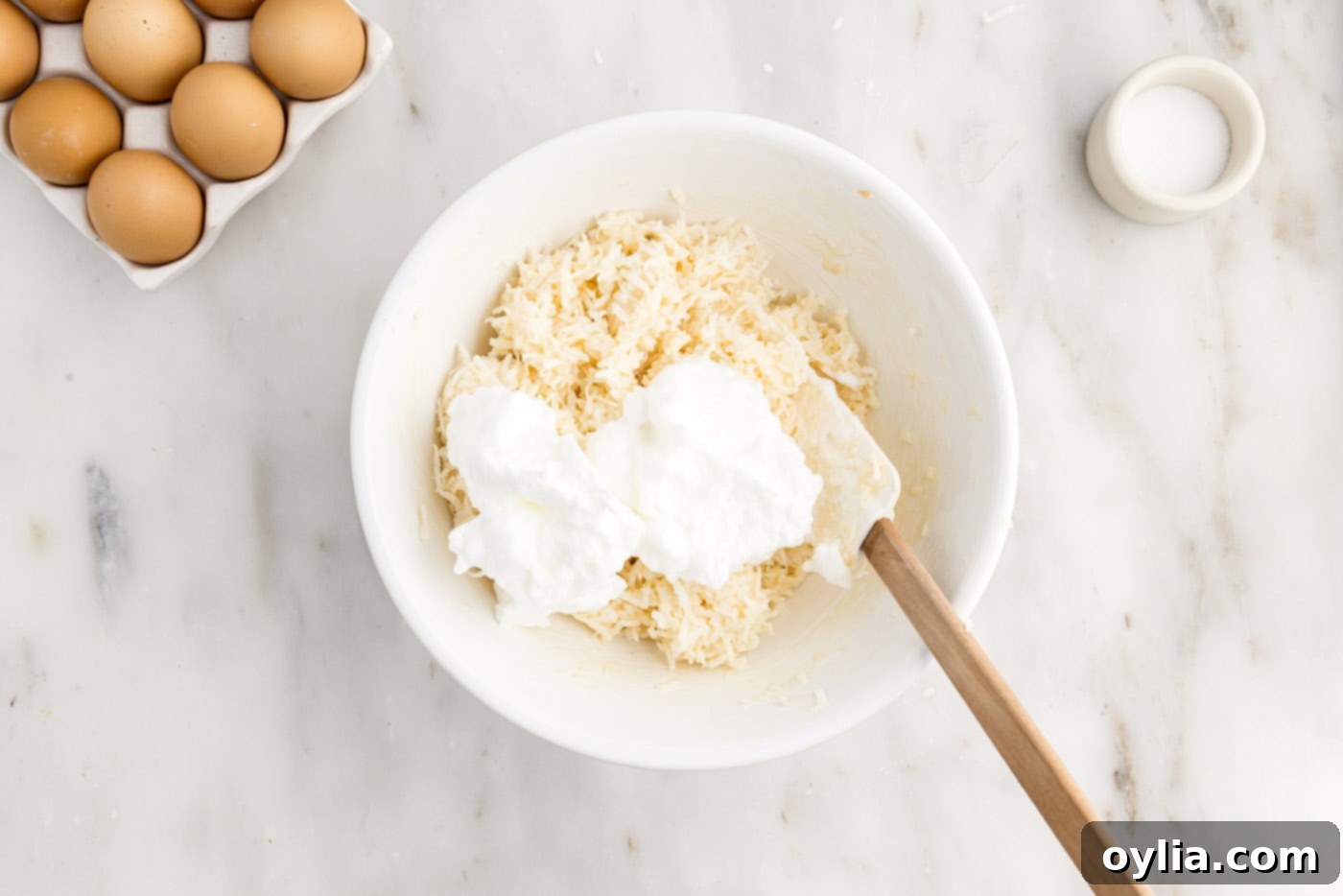 Rubber spatula folding whipped egg whites into shredded coconut mixture