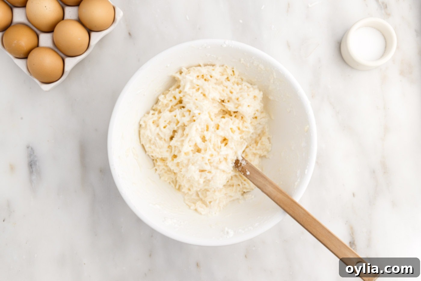 Combined coconut macaroon ingredients in a bowl with rubber spatula